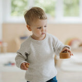 Child holding a medium sized Grimms natural wooden bowl