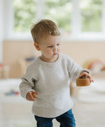 Child holding a medium sized Grimms natural wooden bowl