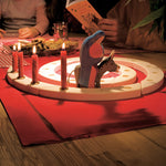 A Grimm's Natural Wooden Spiral set up on a table decorated with red Grimm's candles in brass holders and an Ostheimer donkey and Mary wooden figure. 