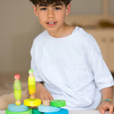 Loose Grimms handcrafted wooden conical pieces in neon green with peg dolls on top and a child in the background