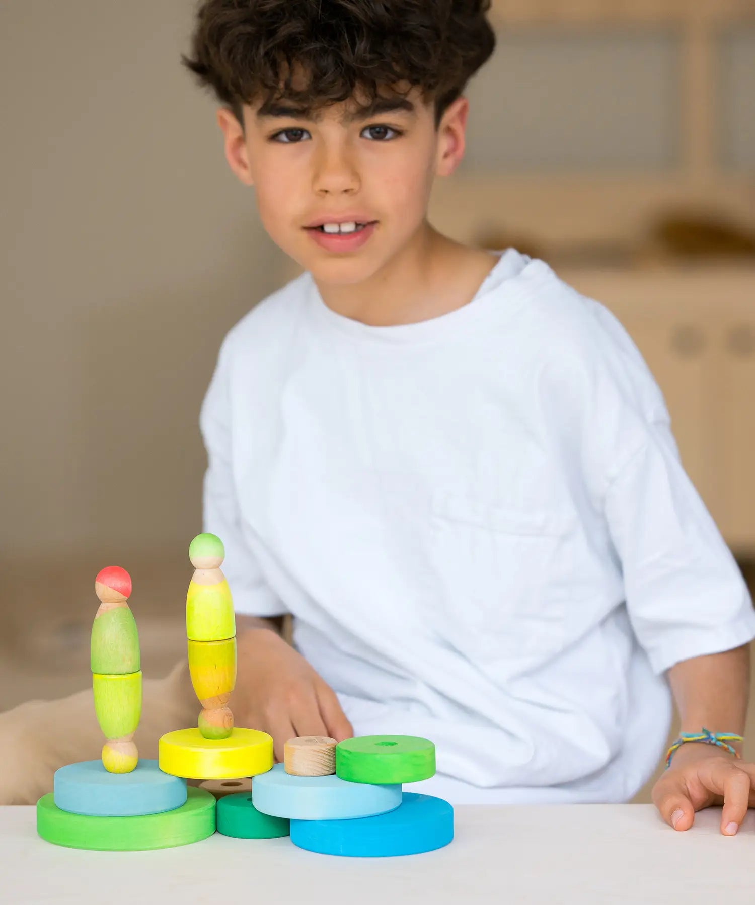 Loose Grimms handcrafted wooden conical pieces in neon green with peg dolls on top and a child in the background