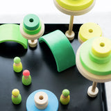 A small world made from neon green Grimms wooden conical pieces, arches and peg dolls