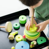 Child stacking the Grimms handcrafted wooden neon green conical pieces 