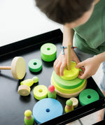 Child stacking the Grimms handcrafted wooden neon green conical pieces 