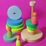 Grimms handcrafted wooden neon green conical tower stacking toy with a natural base with neon peg dolls standing near