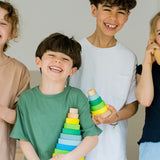 Children holding the large and small Grimms neon green conical stacking tower