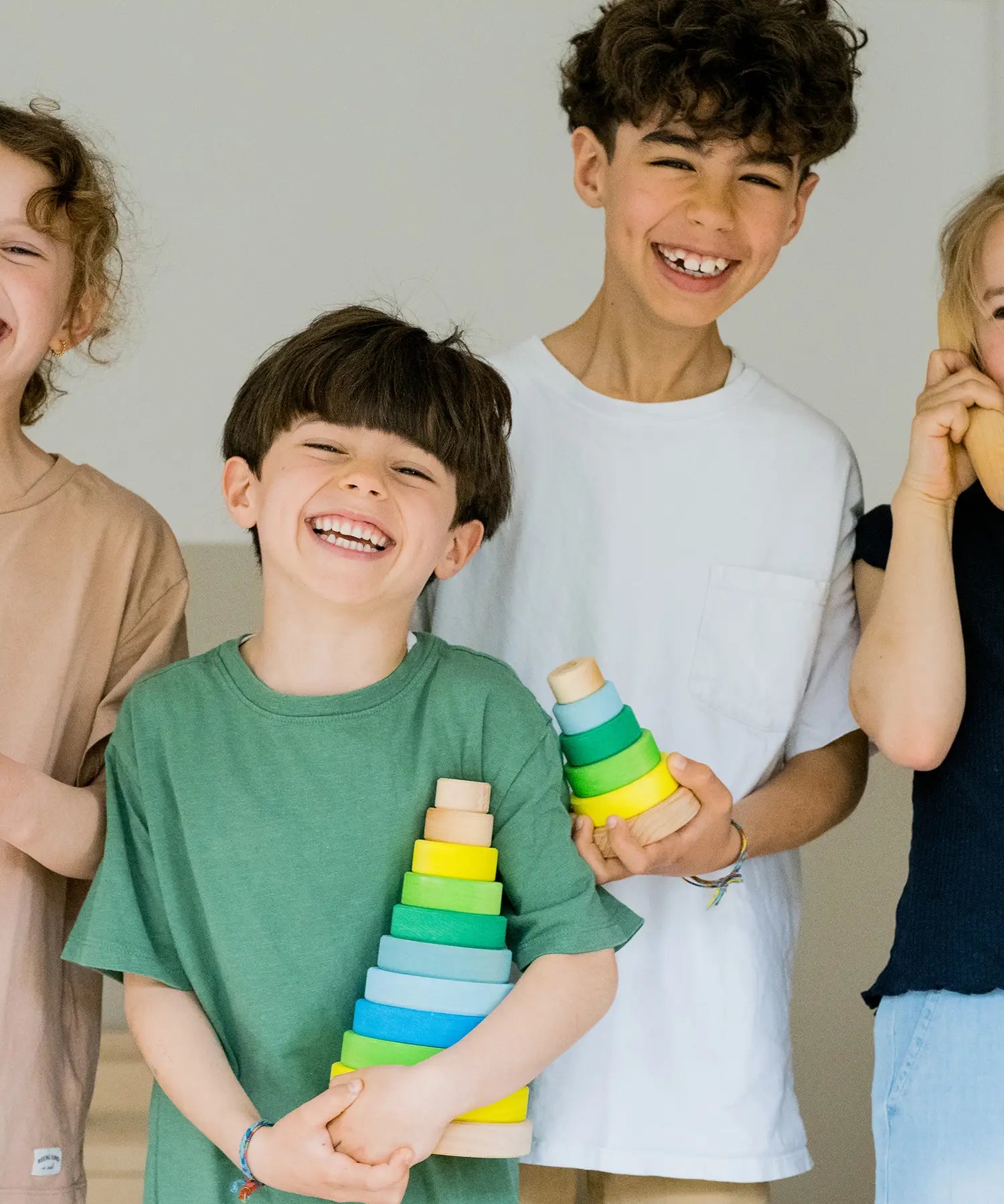 Children holding the large and small Grimms neon green conical stacking tower