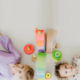 Children lying on the floor with the Grimms neon pink and green conical towers next to their heads
