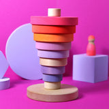Inverted stack using neon pink Grimms handcrafted wooden conical pieces standing on the natural round base