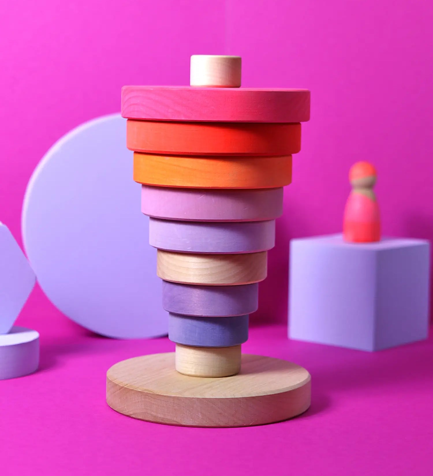 Inverted stack using neon pink Grimms handcrafted wooden conical pieces standing on the natural round base