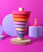 Inverted stack using neon pink Grimms handcrafted wooden conical pieces standing on the natural round base