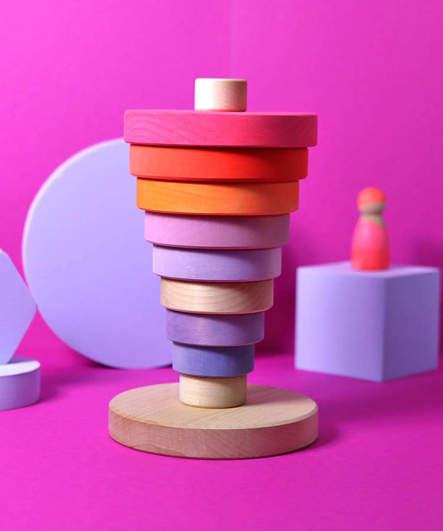 Inverted stack using neon pink Grimms handcrafted wooden conical pieces standing on the natural round base