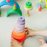 Child holding a stack made from loose Grimms neon pink wooden conical pieces