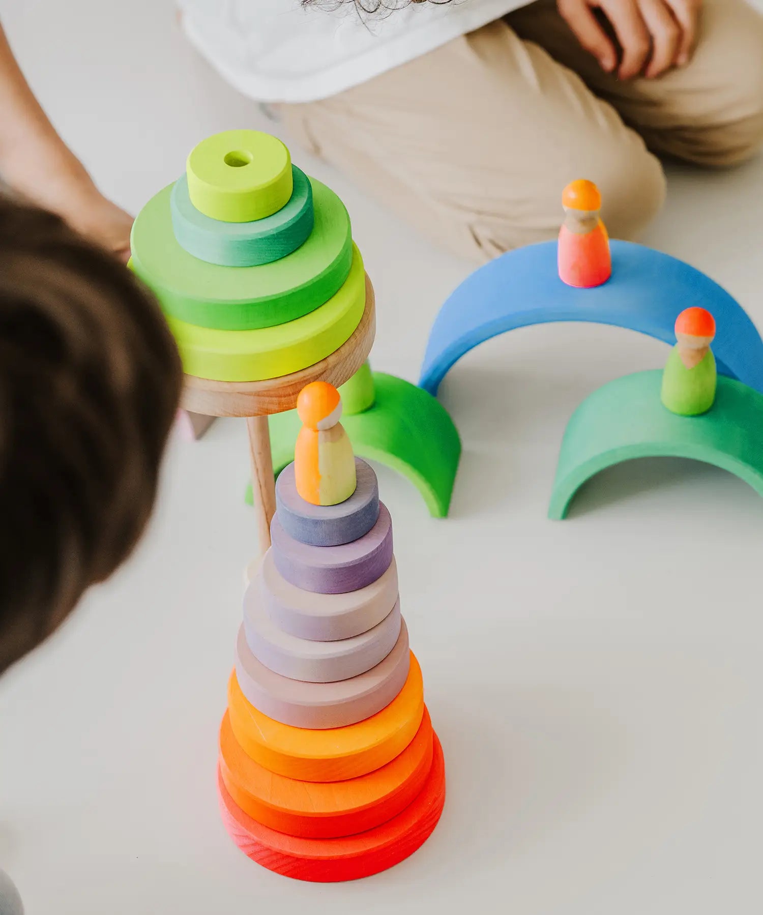 Stack of Grimms wooden neon pink conical pieces standing  next to loose neon green building blocks