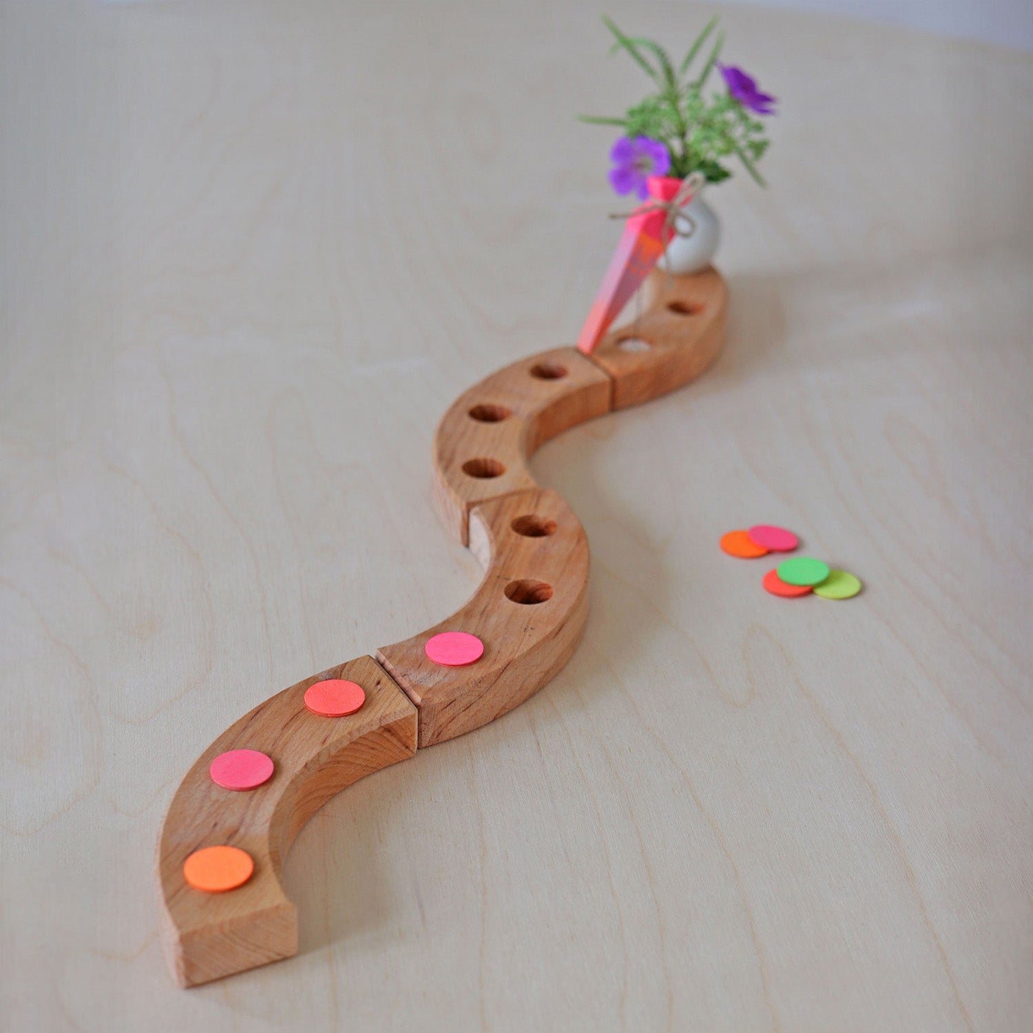 Grimm's Neon Celebration Confetti Dots. The dots sit on top of a celebration ring on a wooden table.