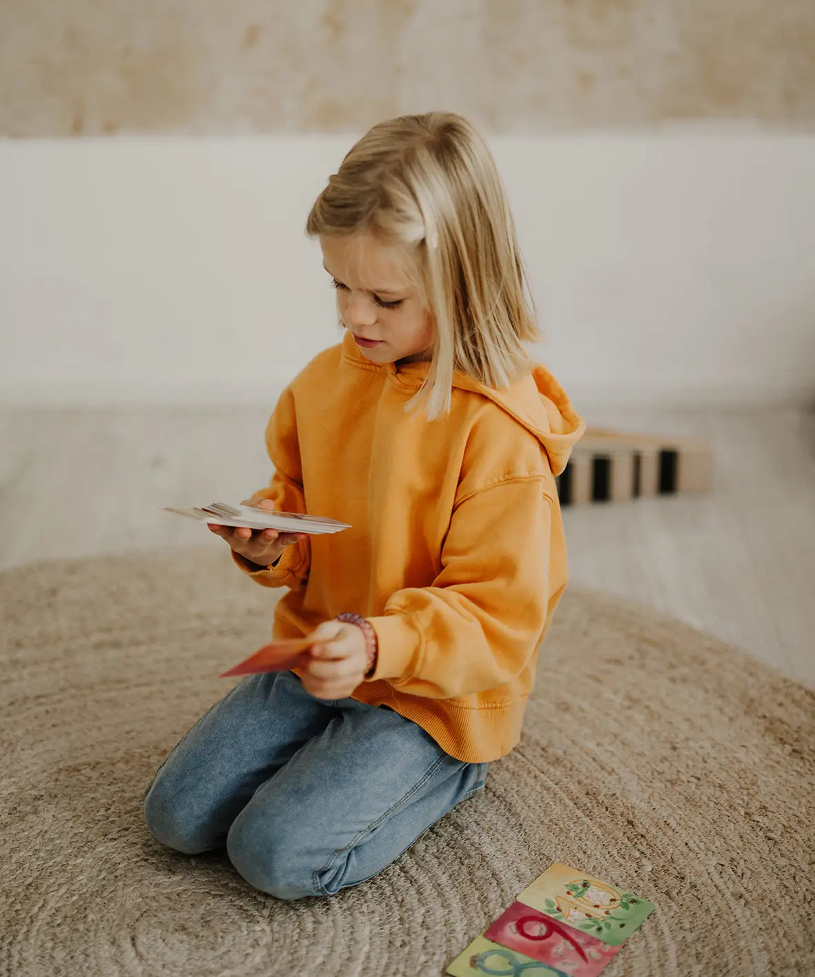 Child holding a pile of Grimms number leaning card showing scale