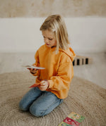 Child holding a pile of Grimms number leaning card showing scale