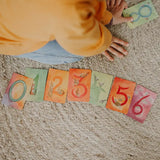 Child sorting the Grimms number cards from 0 to 6. Each card showing a corresponding number of illustrated animals