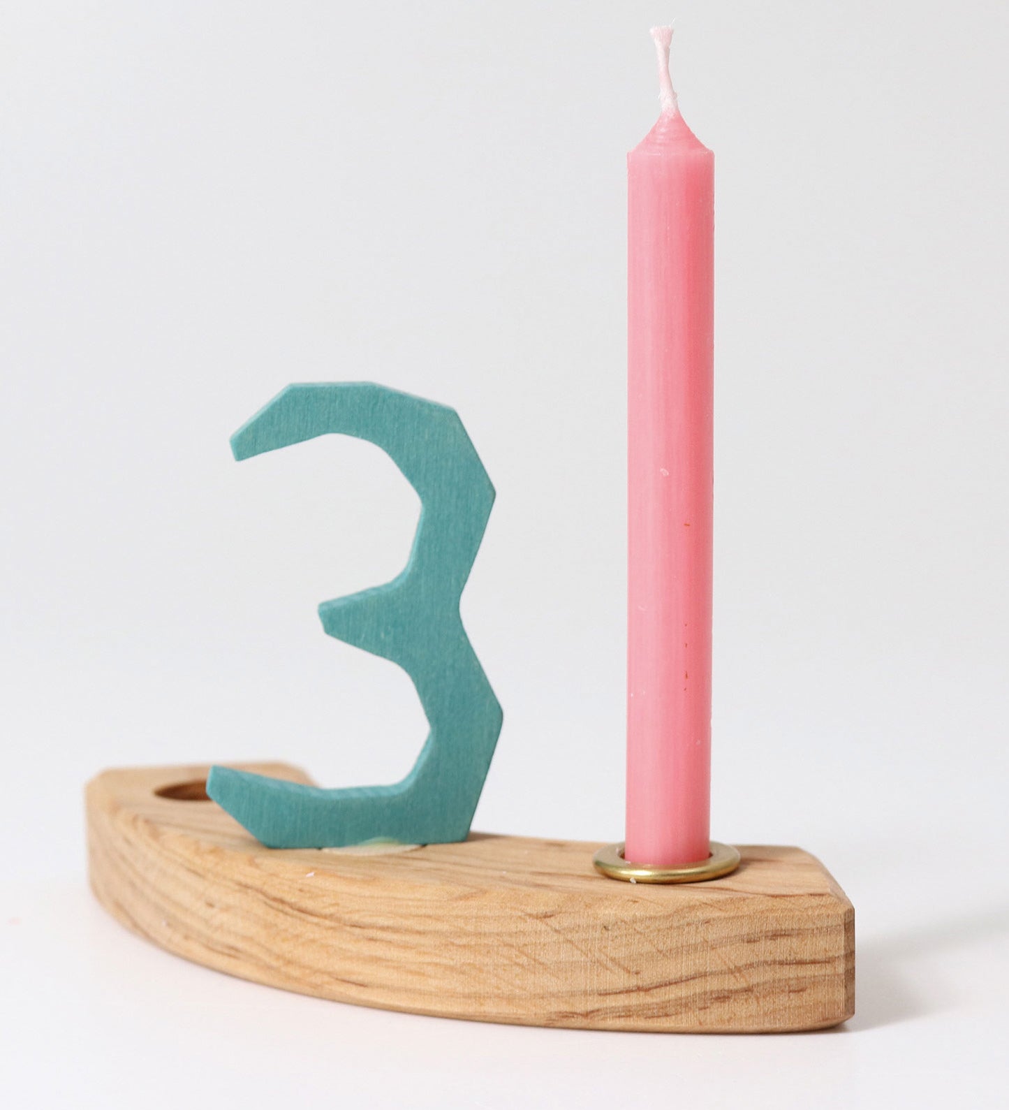 A pink Grimm's Old Rose 10% Beeswax Candles placed on a pieces of a natural celebration ring with a number 3 decorative figure in blue. 