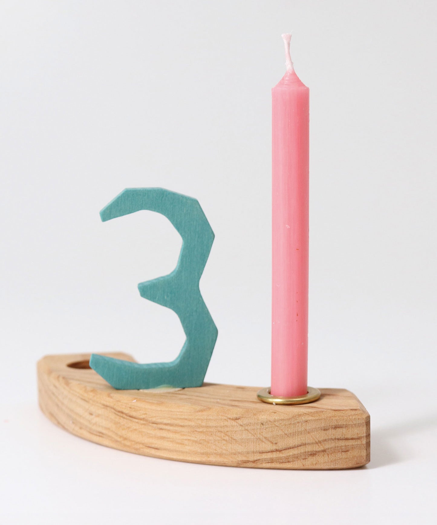 A pink Grimm's Old Rose 10% Beeswax Candles placed on a pieces of a natural celebration ring with a number 3 decorative figure in blue. 