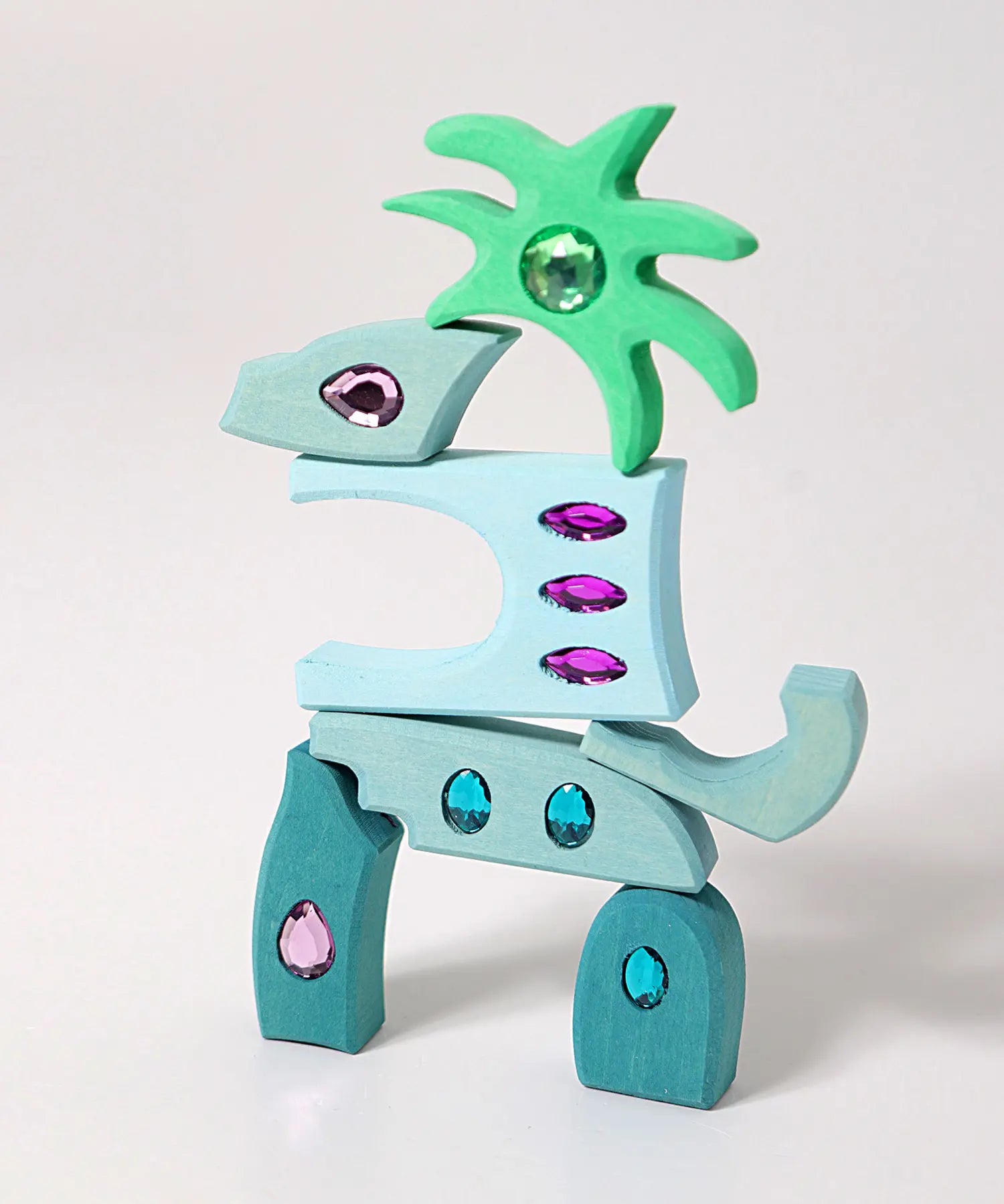 Pieces from the Grimm's orient sparkling building set wooden toy used to create a dinosaur shaped stack.