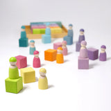 Loose wooden Grimms pastel cubes with matching peg dolls standing on top. 