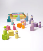 Loose wooden Grimms pastel cubes with matching peg dolls standing on top. 
