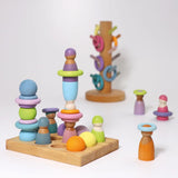 A pastel coloured play setup using Grimms small rainbow balls, rings, sorting board peg dolls