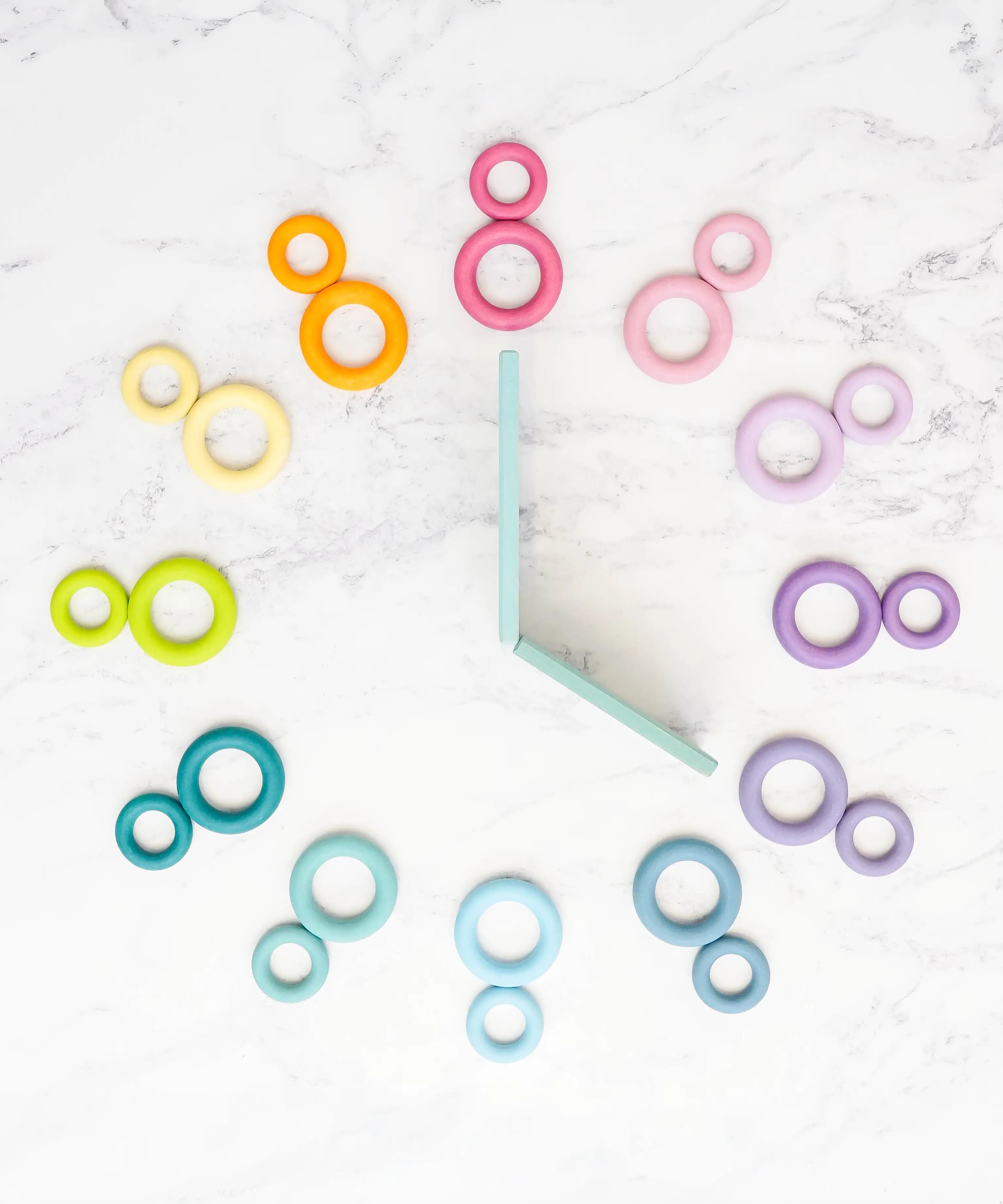 A flatlay showing a clock made from Grimms wooden pastel building boards and ring pieces