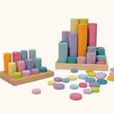 Grimm's large building rollers pastel in a wooden storage tray next to the smaller version of the set.