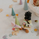 Grimms handcrafted wooden confetti dots in a pastel palette scattered on a table with a small doll decorative figure 
