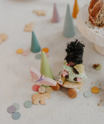 Grimms handcrafted wooden confetti dots in a pastel palette scattered on a table with a small doll decorative figure 