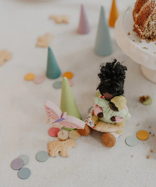 Grimms handcrafted wooden confetti dots in a pastel palette scattered on a table with a small doll decorative figure 