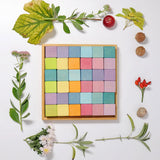 A flat lay using a Grimms wooden pastel 36 cube set with flowers and leaves around the frame