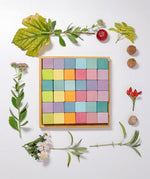 A flat lay using a Grimms wooden pastel 36 cube set with flowers and leaves around the frame