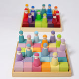 A rainbow and pastel Grimms 36 cube set in their wooden frames with peg dolls on top
