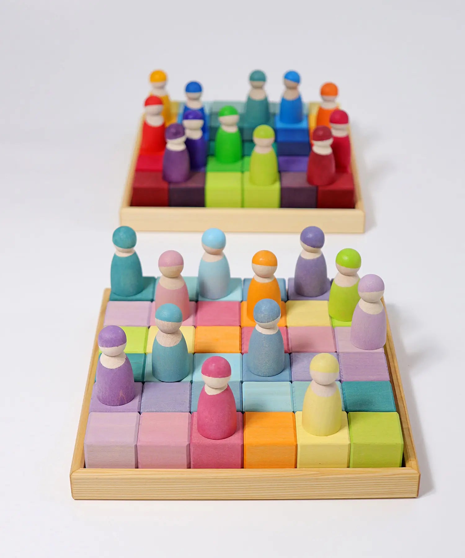 A rainbow and pastel Grimms 36 cube set in their wooden frames with peg dolls on top