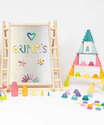 A pastel coloured display using various Grimms wooden pieces and blocks and a Triclimb climbing frame