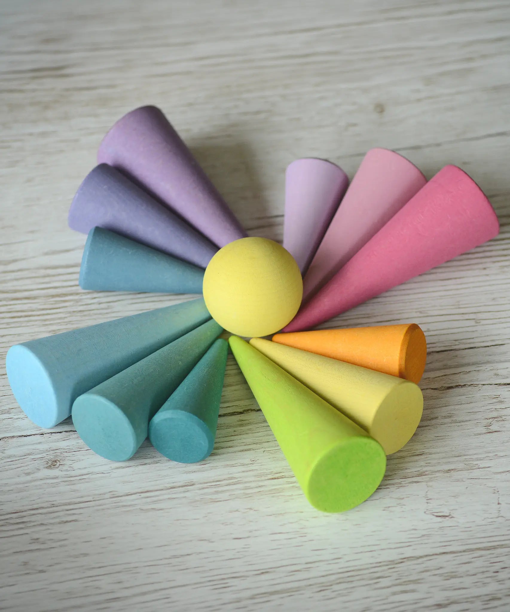 Grimms wooden pastel forest pieces laid flat with a yellow ball in the middle