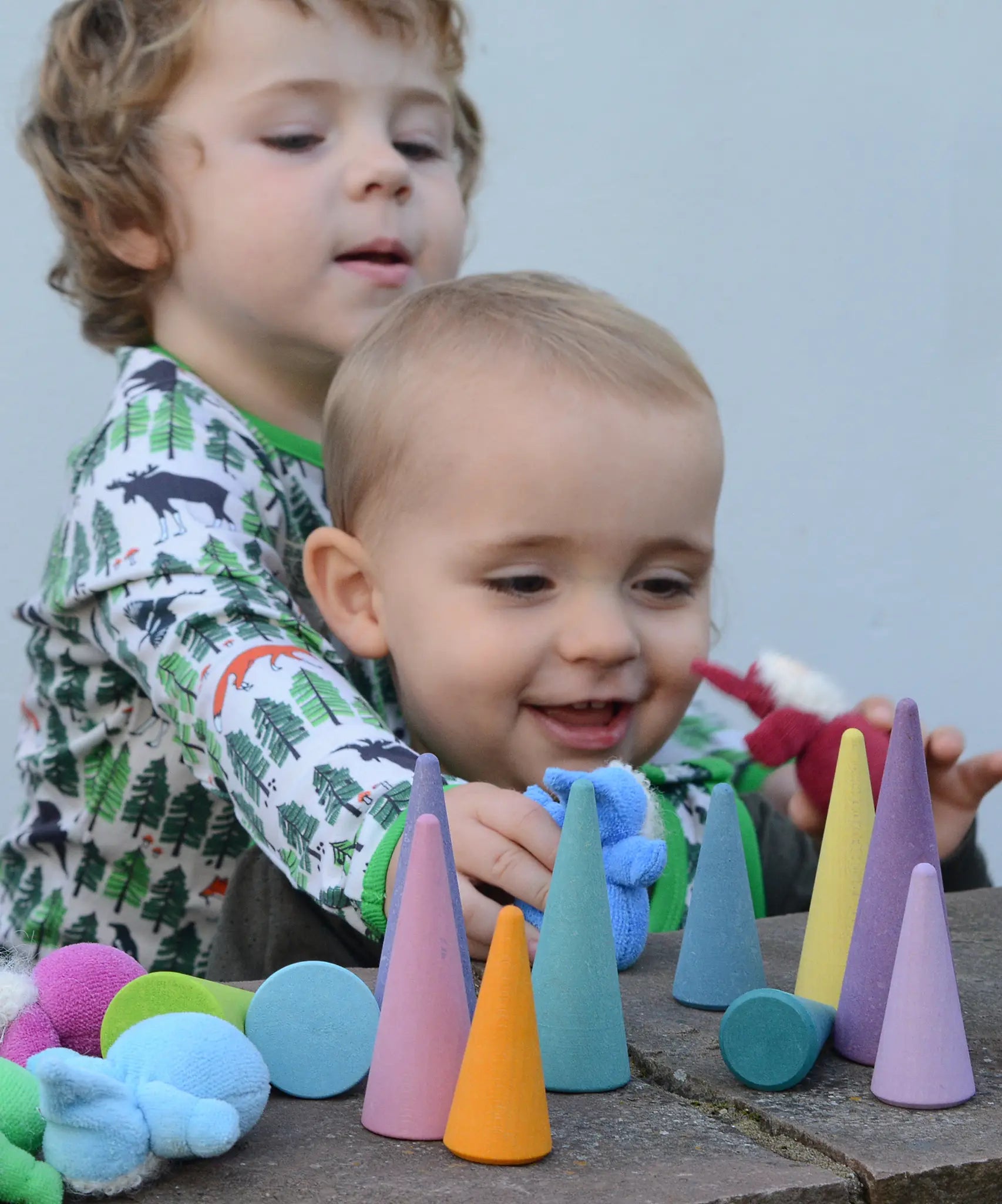 Children playing with the Grimms pastel forest set on a wall with plush dwarf dolls