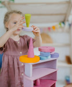 Child holding a light pink wooden disk with a loose Grimms forest piece on top 