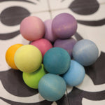 The Grimm's pastel grasper beads wooden grasping toy placed on a patterned tiled surface. 