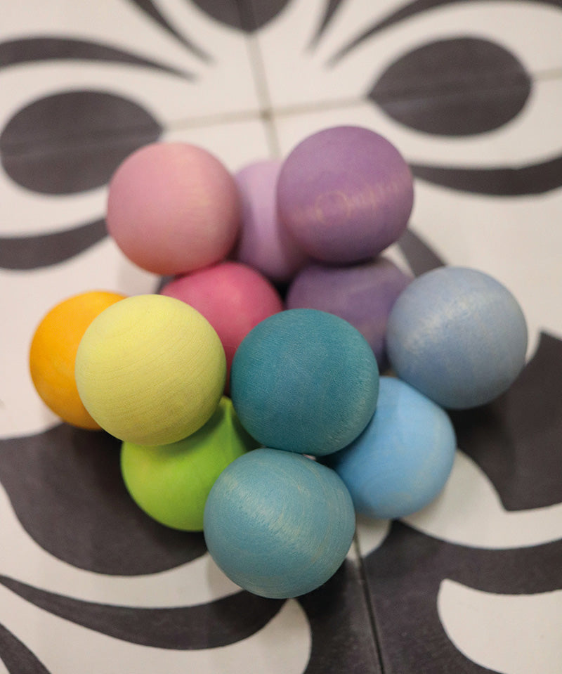 The Grimm's pastel grasper beads wooden grasping toy placed on a patterned tiled surface. 