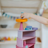 Child placing a block on top of a stack made from Grimms pastel semi circles and arch pieces