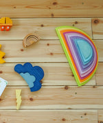 Flatlay showing a Grimms pastel semi circle set on a wooden floor next to other loose building blocks