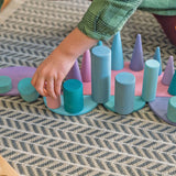 Child placing a pastel building block on a Grimms pastel semi circle piece