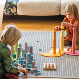 Children stacking wooden building blocks on Grimms pastel semi circle pieces 