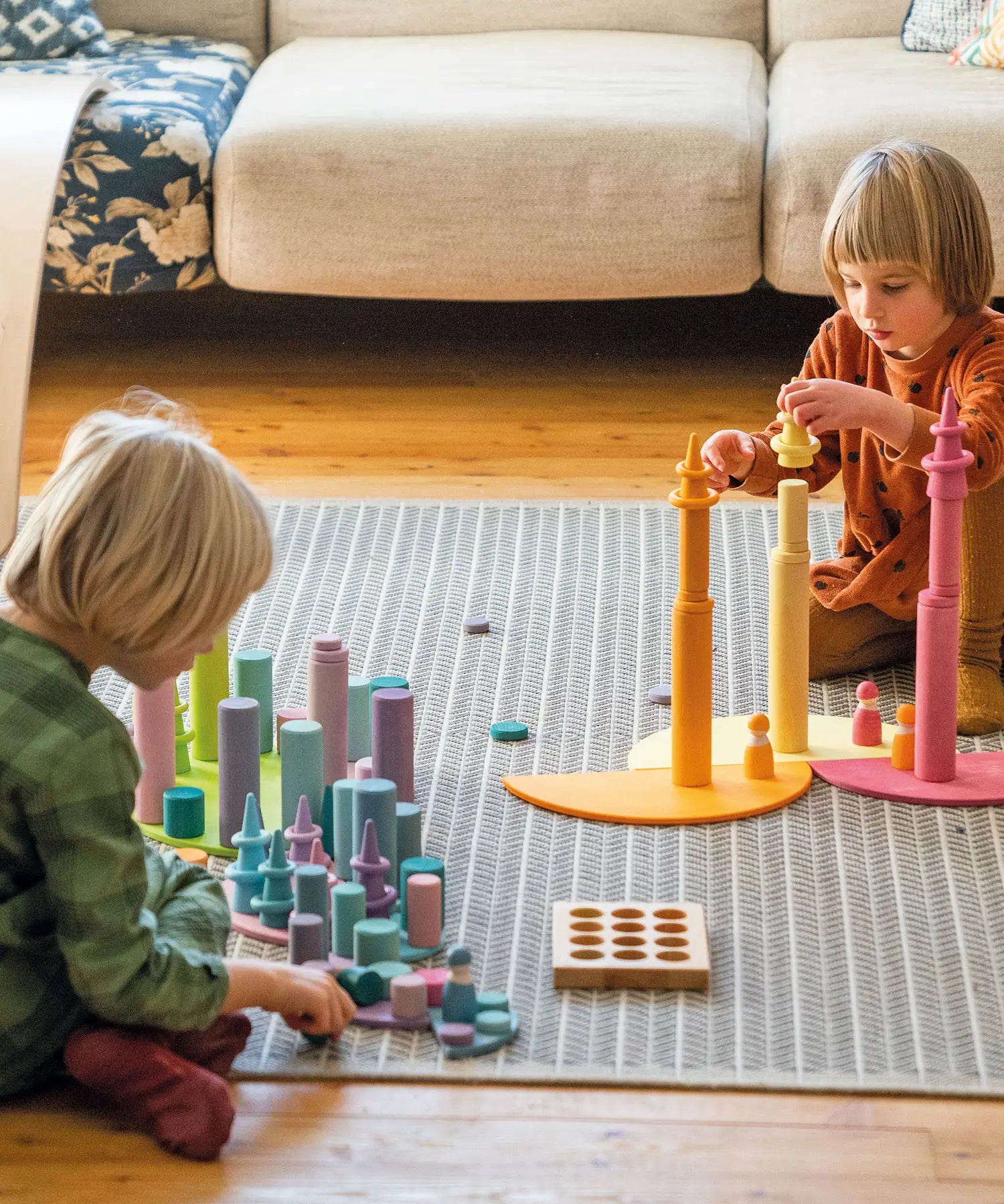 Children stacking wooden building blocks on Grimms pastel semi circle pieces 