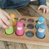 Child sorting pastel coloured wooden peg dolls in the Grimms handcrafted sorting board