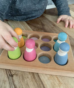 Child sorting pastel coloured wooden peg dolls in the Grimms handcrafted sorting board